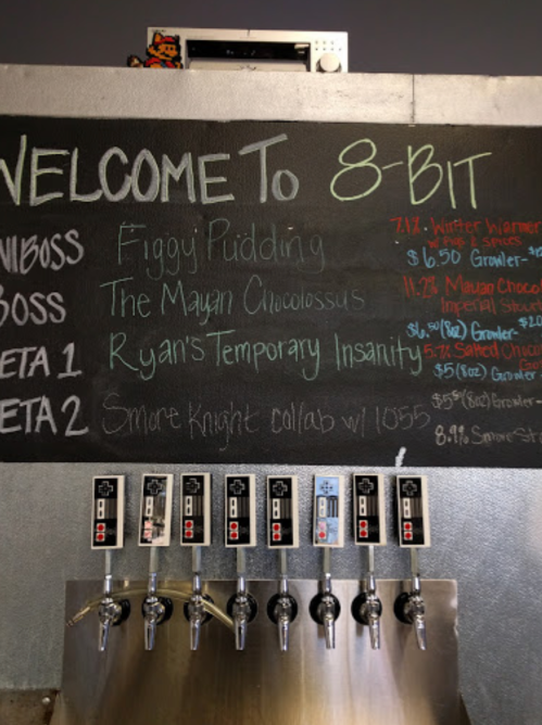 Chalkboard menu at 8-Bit featuring beer options and prices, including Figgy Pudding and Ryan's Temporary Insanity.
