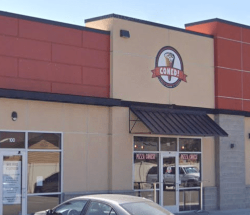 Exterior of a restaurant named "Coned!" with a sign featuring a pizza cone logo. A car is parked in front.