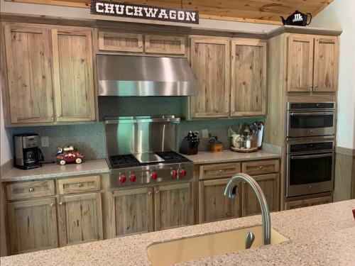 Modern kitchen with wooden cabinets, stainless steel appliances, and a central island featuring a sink. "CHUCKWAGON" sign above.
