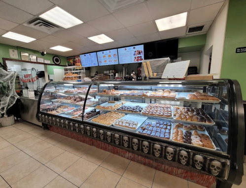 A bakery display case filled with various donuts and pastries, with a Halloween-themed decoration at the bottom.
