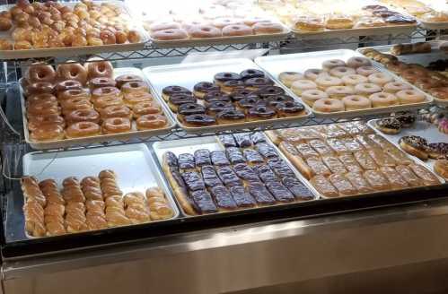 A display case filled with various types of donuts, including glazed, chocolate-covered, and cream-filled options.