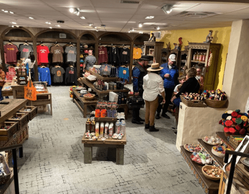A cozy shop interior with shelves of clothing and crafts, featuring customers browsing and chatting.