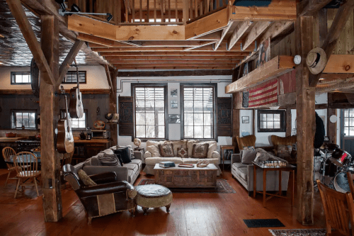 Cozy rustic living room with wooden beams, comfortable seating, and large windows, featuring a warm, inviting atmosphere.