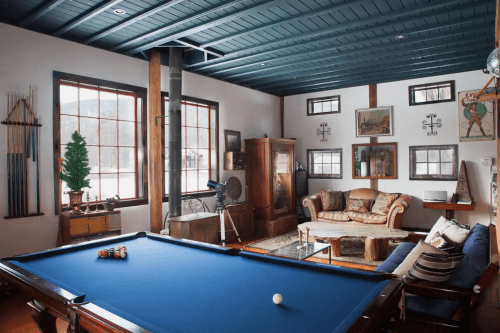 Cozy game room featuring a blue pool table, comfortable seating, and large windows with a view.