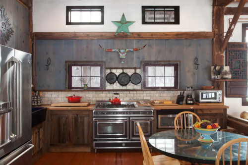 A rustic kitchen with wooden accents, a large stove, and a dining table with fruit, featuring a star and bull skull decor.