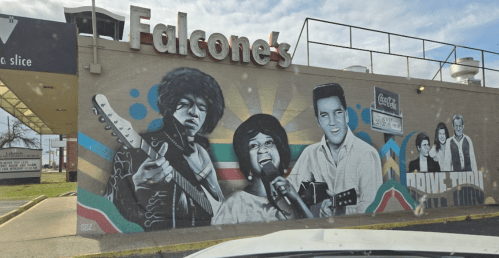 Mural on a building featuring iconic musicians, including a guitarist and a singer, with colorful background elements.