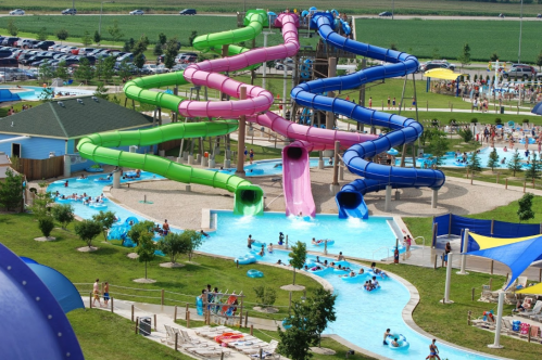 Aerial view of a water park featuring colorful slides, pools, and people enjoying the attractions on a sunny day.