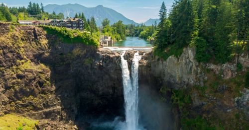 Sunny day of Snoqualmie Falls in Snoqualmie, Washington, with the Salish Lodge and mountains in the background