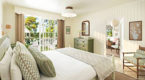 Bright, airy bedroom with a large bed, green accents, and a view of a garden through open doors. Cozy and inviting atmosphere.