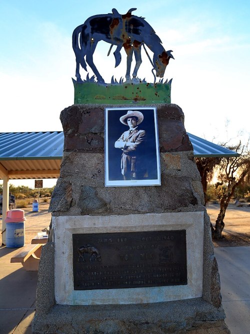 A monument featuring a horse sculpture and a photo of a man, with a plaque commemorating his memory.