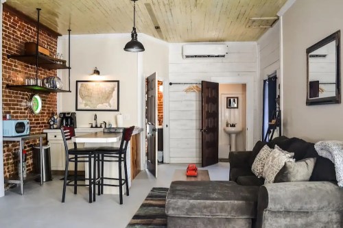 Cozy apartment interior featuring a kitchen, dining area, and living space with exposed brick and modern decor.