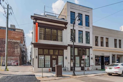 A modern two-story building with large windows, located at a street corner, surrounded by urban architecture.