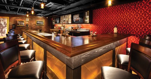 The polished wood bar and red damask wallpaper at The Underground Speakeasy in Las Vegas, Nevada.