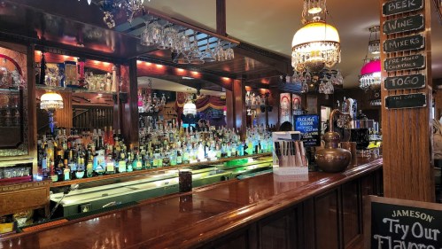 A well-stocked bar with colorful bottles, elegant lighting, and a polished wooden counter.