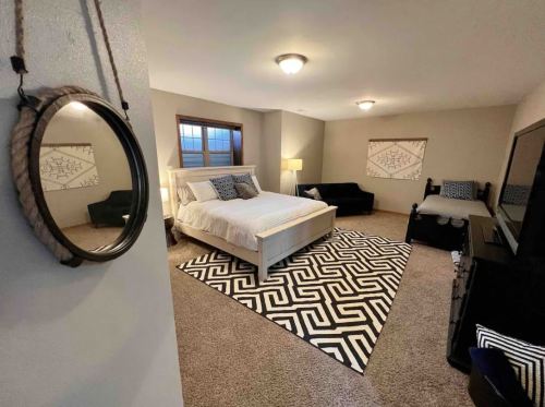 Cozy bedroom featuring a bed, two lamps, a rug, and a mirror, with neutral walls and decorative artwork.