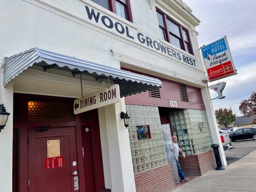 Exterior of Wool Growers Rest restaurant, featuring a sign, entrance, and a person exiting the building.