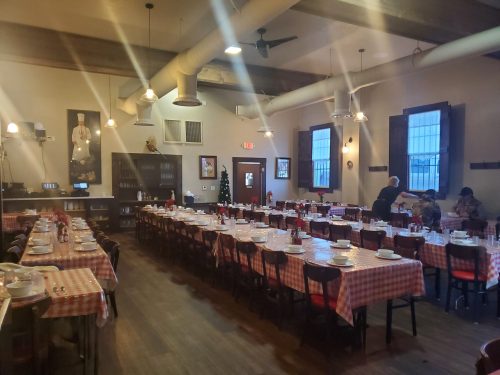 A spacious restaurant with checkered tablecloths, set tables, and a warm, inviting atmosphere.