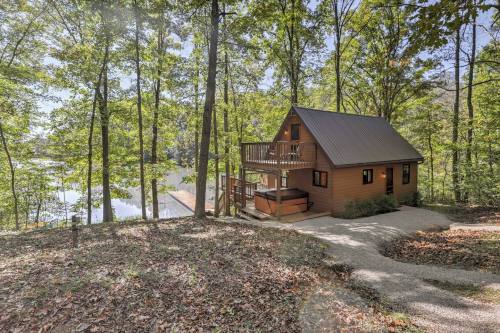 A cozy cabin nestled among trees by a serene lake, featuring a deck and a gravel path leading up to it.