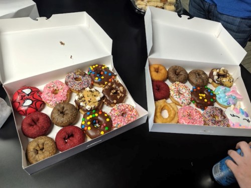 Two open boxes filled with a variety of colorful donuts, including sprinkles, chocolate, and themed designs.