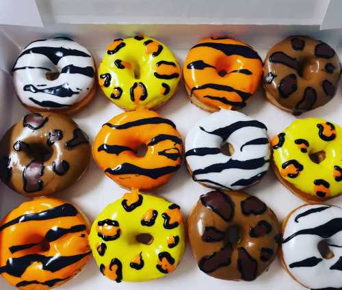A box of colorful donuts with tiger stripe patterns in yellow, orange, black, and brown.