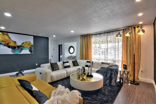 Modern living room featuring a yellow sectional sofa, white circular coffee table, and elegant decor with gold accents.