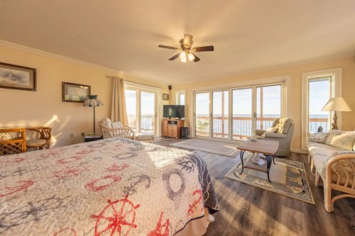 Cozy bedroom with a quilt, seating area, TV, and large windows overlooking a scenic view.