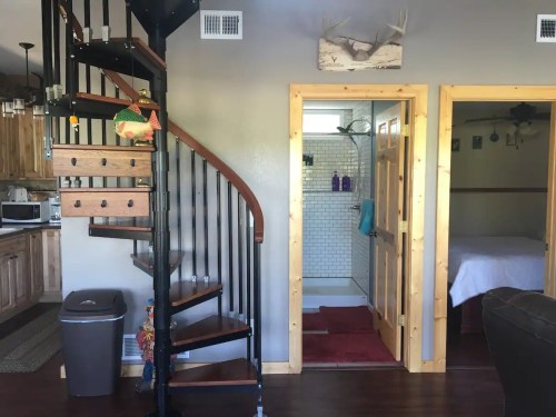 A cozy interior featuring a spiral staircase, wooden accents, and a bathroom door leading to a bedroom.