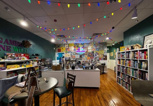 A cozy game café with colorful lights, shelves of board games, and a vibrant mural on the wall.
