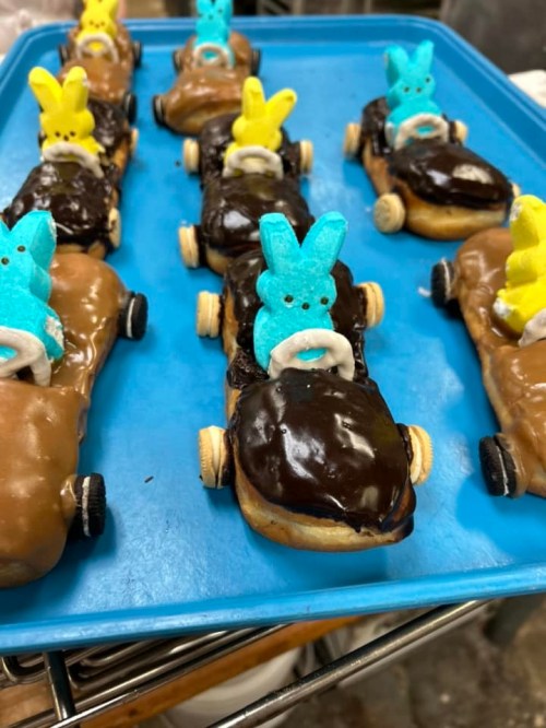 Colorful dessert cars made from donuts, chocolate, and marshmallow bunnies, arranged on a blue tray.