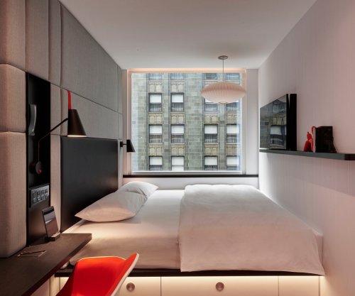 A modern hotel room featuring a bed, sleek decor, and a large window with a city view.