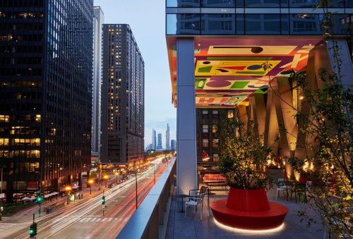 Cityscape at dusk featuring modern buildings, a vibrant ceiling, and a stylish outdoor seating area.