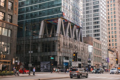 Modern urban building with colorful architectural features, surrounded by city streets and pedestrians.
