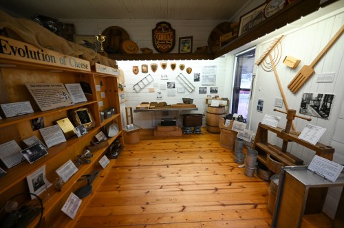 Interior of a museum exhibit showcasing the evolution of cheese, featuring historical tools and informative displays.