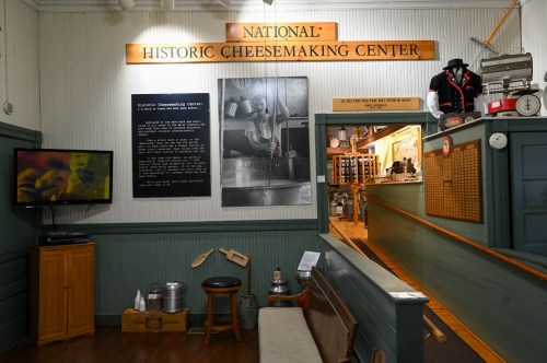 Interior of the National Historic Cheesemaking Center, featuring displays, a TV, and historical cheesemaking tools.