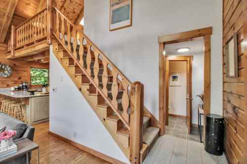 A cozy interior featuring a wooden staircase, open kitchen, and warm wooden walls, creating a welcoming atmosphere.