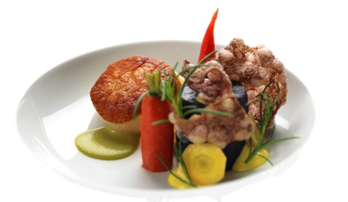 A gourmet dish featuring crispy seafood, colorful vegetables, and sauces, elegantly arranged on a white plate.