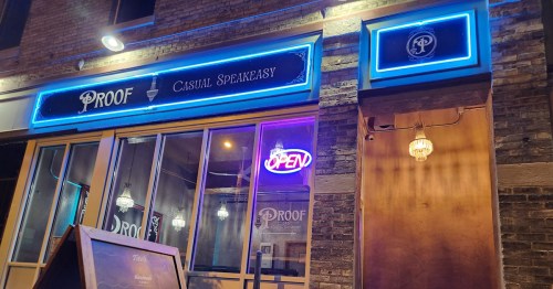 Exterior of a bar named "Proof Casual Speakeasy," featuring neon lights and an open sign.