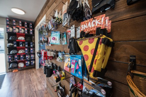 A colorful display of biking accessories and snacks on wooden walls in a shop, with helmets visible in the background.