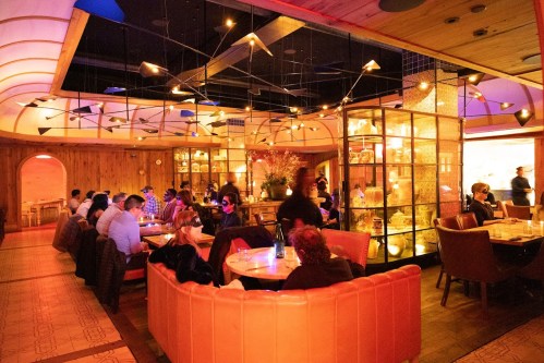 A cozy restaurant interior with warm lighting, featuring a mix of seating and a glass display cabinet.