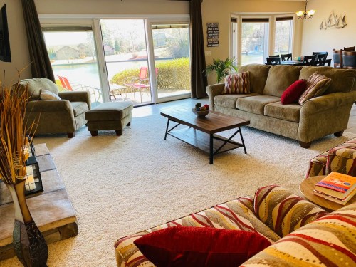 Cozy living room with plush sofas, a coffee table, and large windows overlooking a scenic outdoor view.