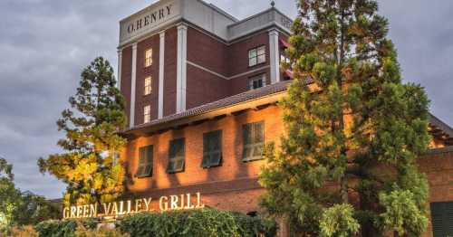 Exterior view of Green Valley Grill with O. Henry Hotel in the background, illuminated by evening lights.