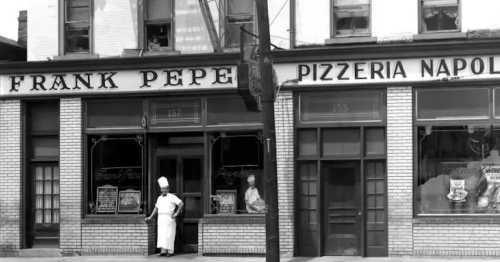 Historic black-and-white photo of Frank Pepe Pizzeria Napoli, featuring a chef in front of the restaurant.