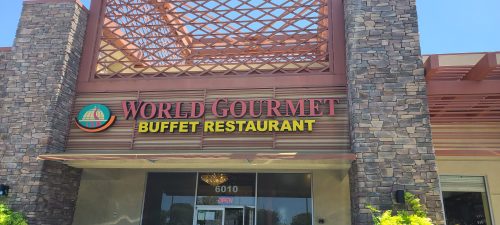 Exterior of World Gourmet Buffet Restaurant, featuring a stone facade and a sign indicating it's open.