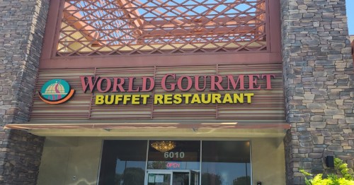 Sign for "World Gourmet Buffet Restaurant" with a stone facade and an "Open" sign visible.