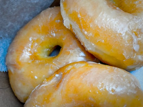 Three glazed donuts stacked together, showcasing a shiny, golden exterior and a classic round shape.