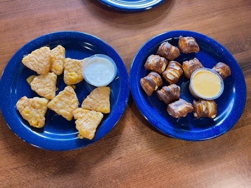 Two blue plates: one with golden, crispy nuggets and dipping sauce, the other with sweet, rolled pastries and sauces.