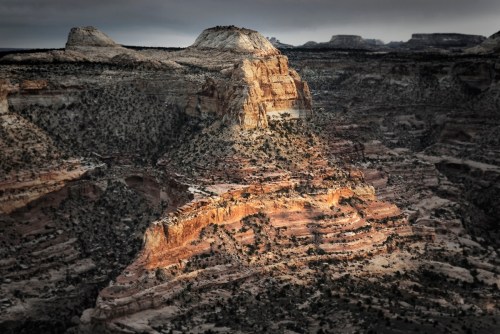 A dramatic landscape of layered rock formations and cliffs under a moody sky, showcasing natural textures and shadows.