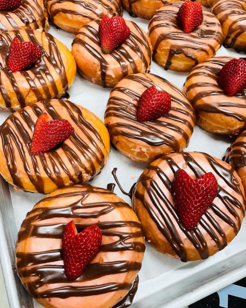 A tray of donuts topped with chocolate drizzle and fresh strawberries.