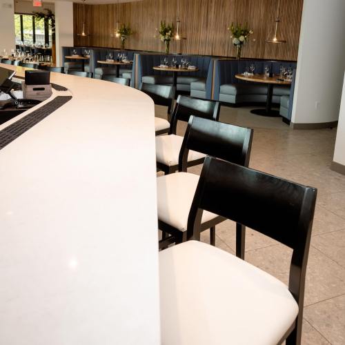 A modern restaurant interior featuring a curved bar, empty tables, and floral centerpieces.