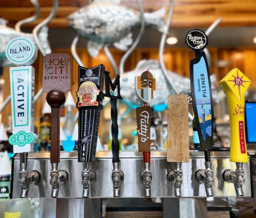 A row of colorful beer taps featuring various brewery logos and designs in a rustic setting.